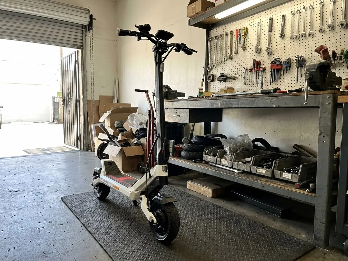 White and black Kaabo-style electric scooter standing in a repair workshop