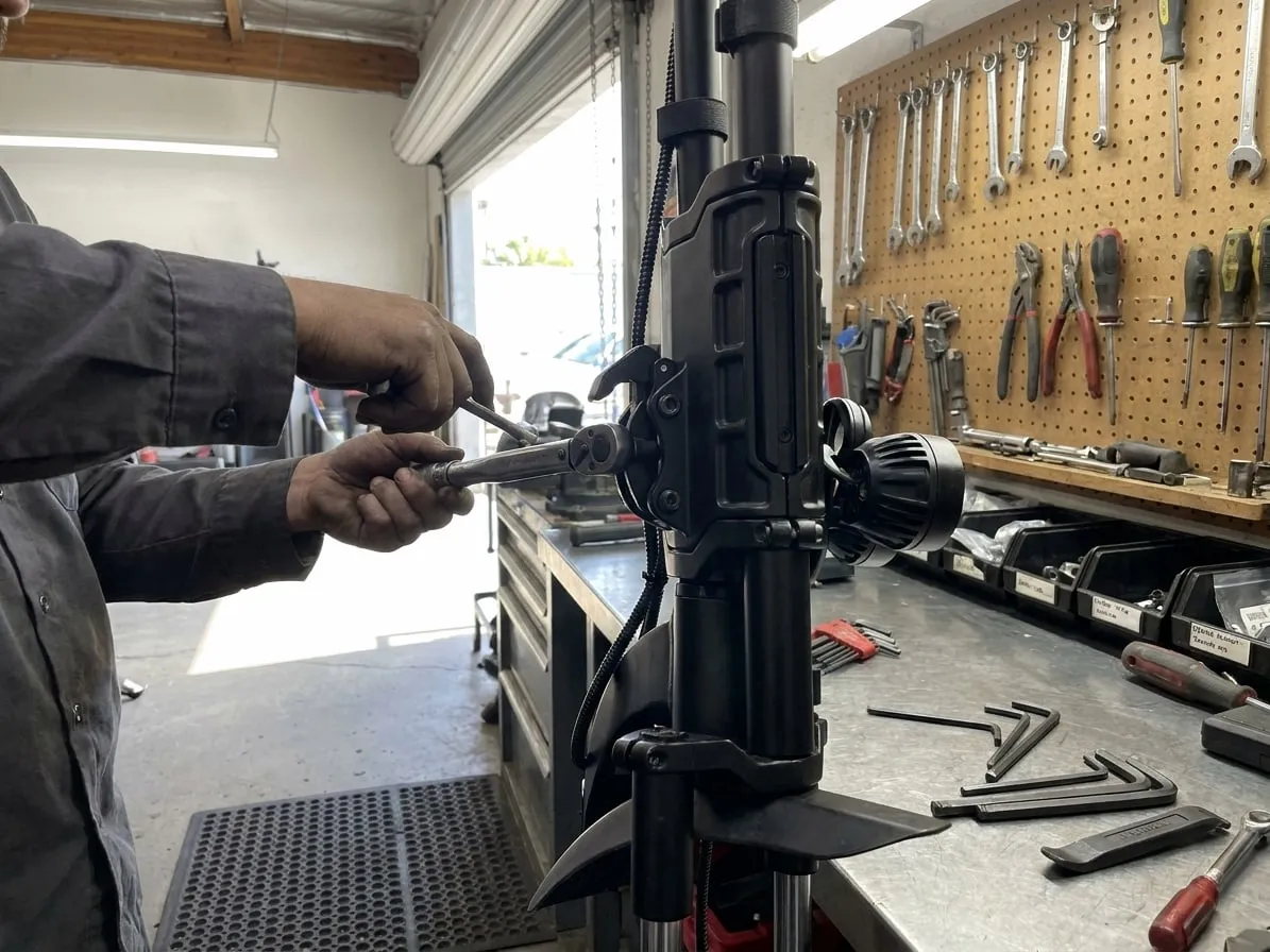Technician tightening the folding-hinge bolts of an off-road electric scooter stem with a torque wrench